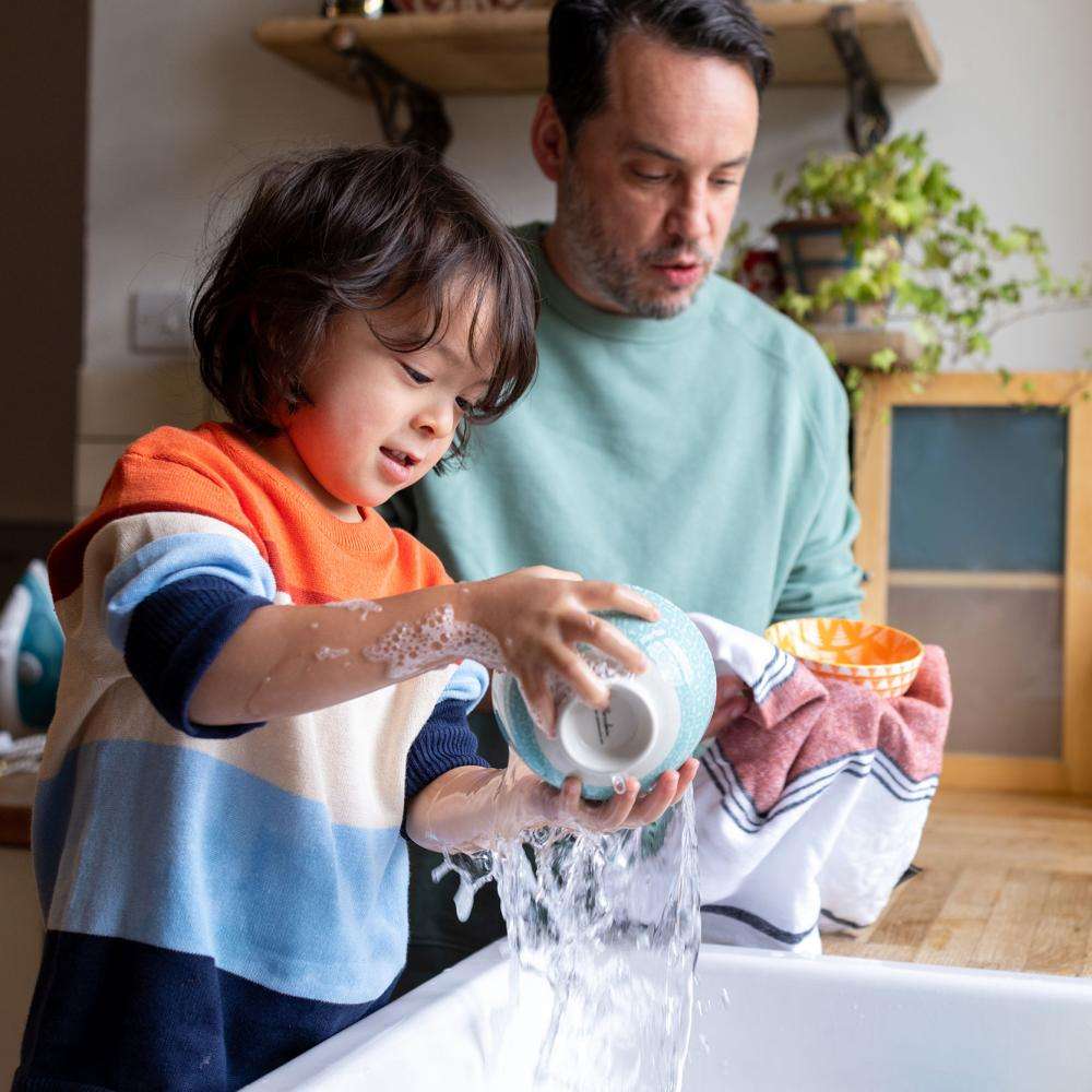 A man and young child wash dishes together