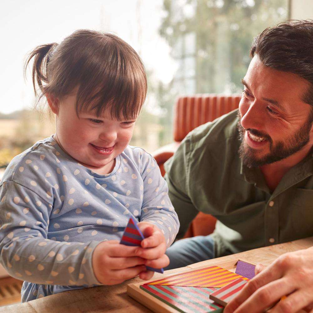 A man smiles and talks to a young girl who is playing with a toy