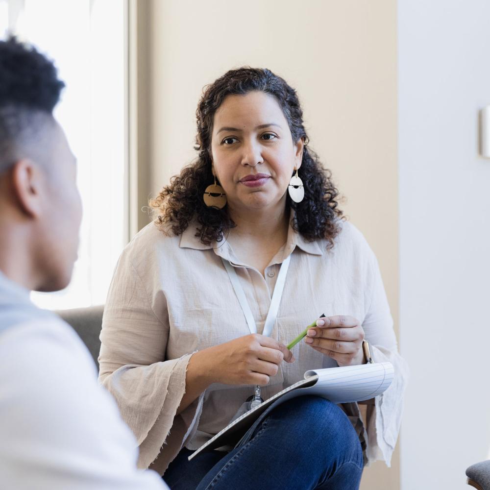 A woman holds a pen and listens to a boy