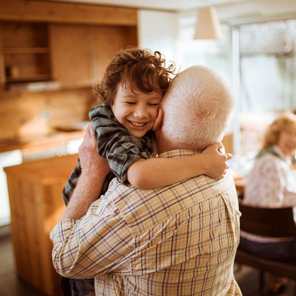 A grandfather picks ups a smiling young boy