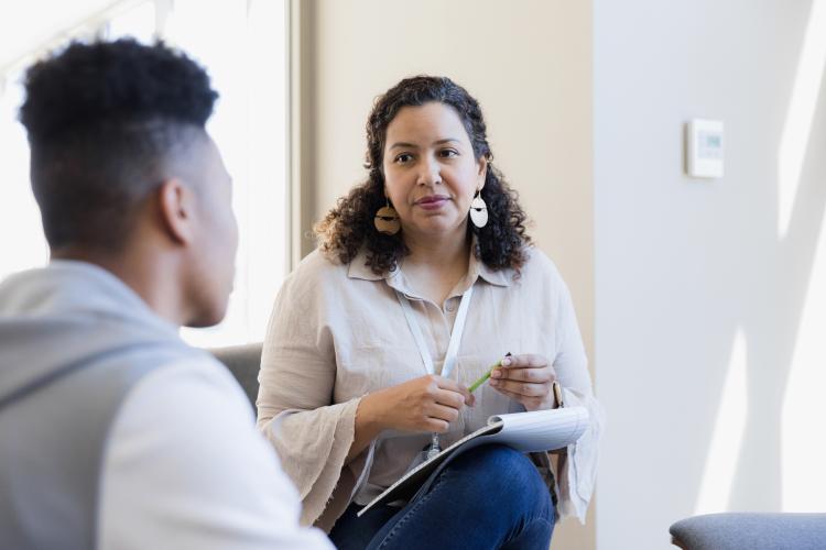 A woman holds a pen and listens to an apprentice providing feedback